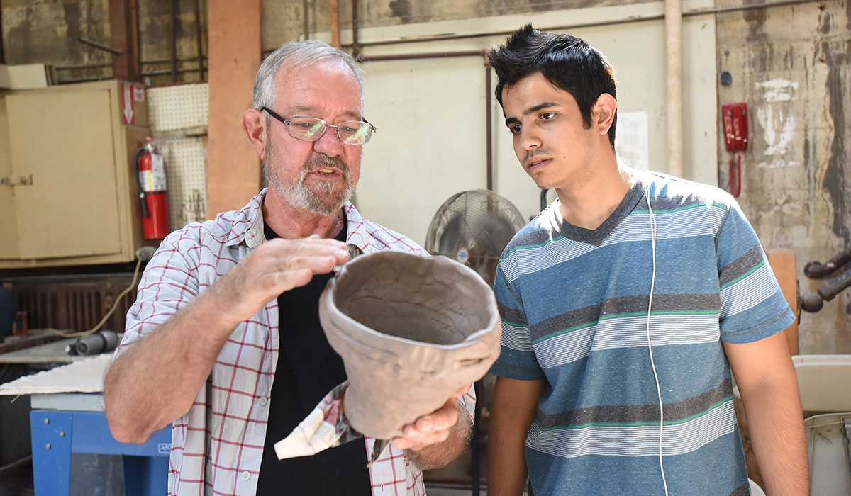 Ceramics teacher and student looking at pot