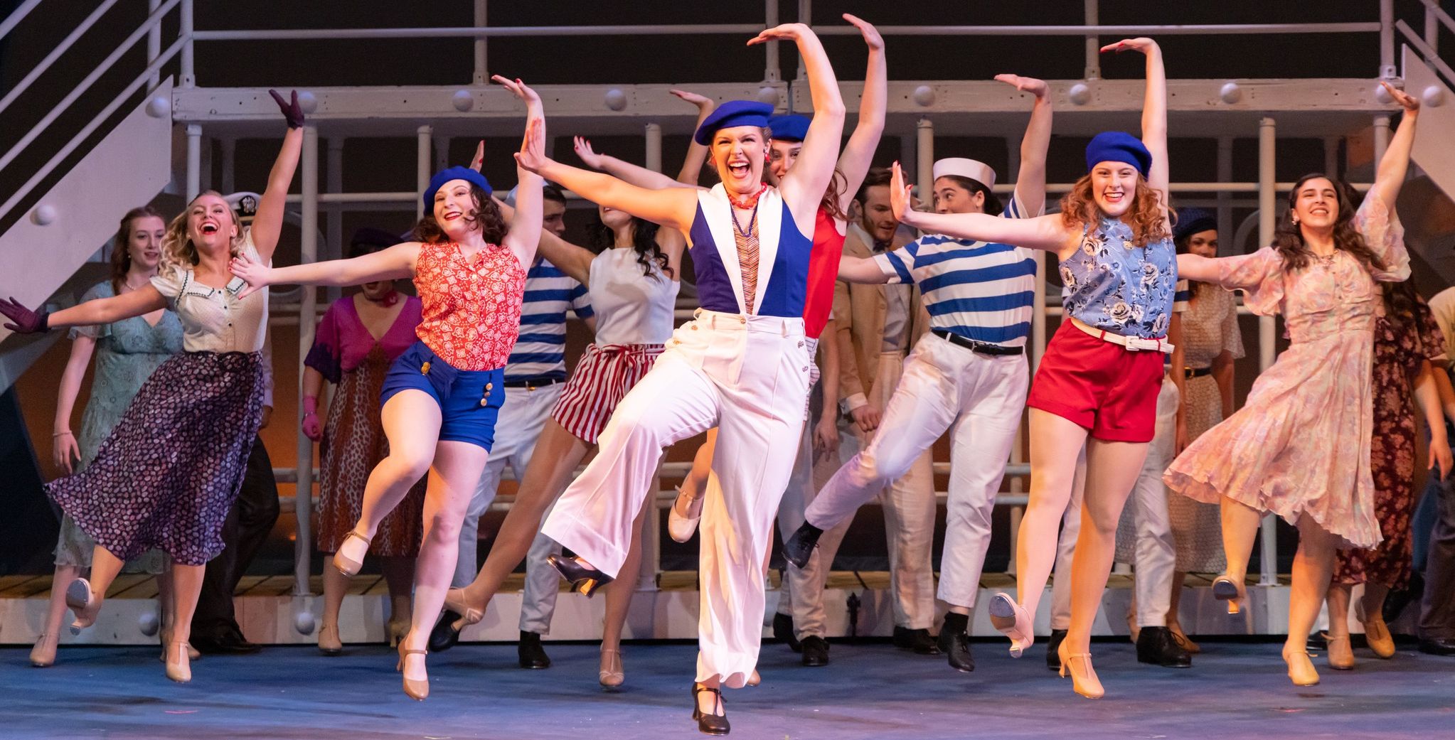 Group dancing on the deck of a ship on stage.